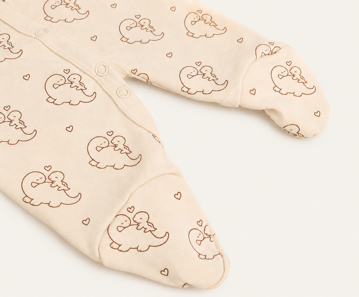 The Dino Footed Onesie, dinosaur-and-heart print in cream